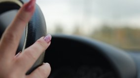 Video, woman hands hold the steering wheel of a car, beautiful fingers with a pink manicure