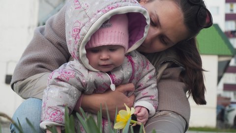 Happy Mom Shows Her Baby A Yellow Flower. Family walk, positive childhood, family love. Sunny day.