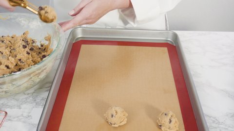 Time lapse. Step by step. Scooping homemade chocolate chip cookies with metal dough scoop to the baking sheet.