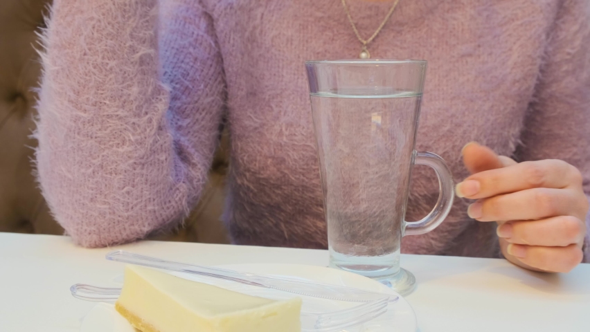 Female hands, close-up, brews black tea bags in a glass glass.