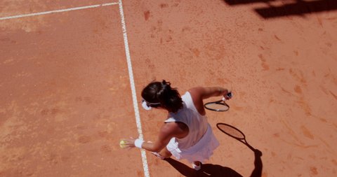 Woman serving ball during tennis match on clay court