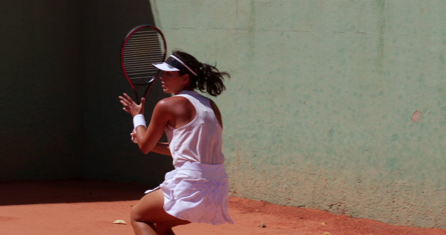 Female tennis player hitting ball on clay court | Shutterstock HD Video #1061258341