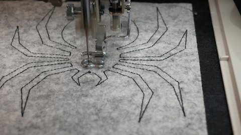 Embroidery machine creating textile design, Sewing machine needle in motion, Spider embroidery for Halloween