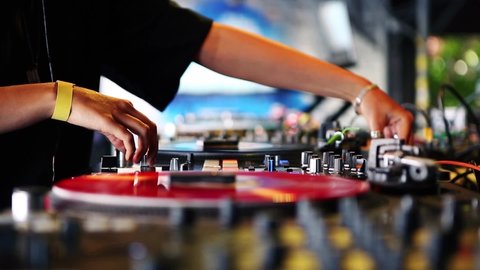 Female dj plays music on party in bar.Royalty free 4K video clip of disc jockey girl playing musical tracks with retro turntables & sound mixer on stage in nightclub.Professional djs turn table player