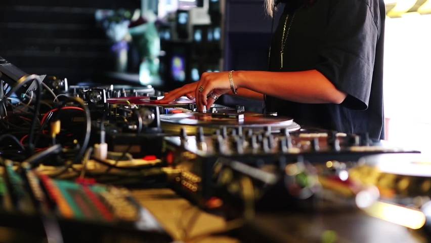 Hip hop dj girl playing music with analog vinyl records on retro turntables.Professional female disc jockey plays musical tracks on party in nightclub with vintage turn table player & sound mixer | Shutterstock HD Video #1061258824