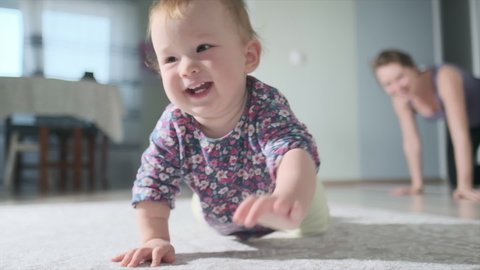 Happy baby crawls in the room. Infant baby plays with family in the house and learns how to crawl quickly during catch up games