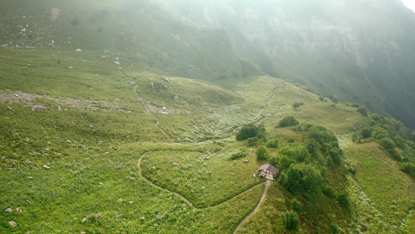 Wonderful landscape with rural house on green hill top of old mountain covered with grass and road in tranquil valley in summer morning bird eye view