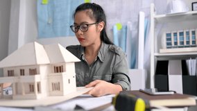 A female Asian  architect looking for home model and check scale. Architect,engineer concept