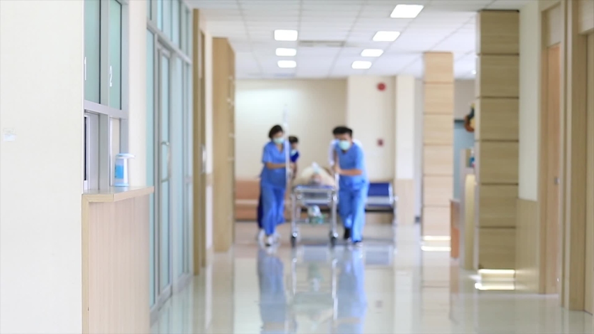 Emergency Department: Group of Doctors, Nurses and Surgeons wearing face mask Move Seriously senior Patient Lying on a Stretcher Through Hospital Corridors. Medical Staff in a Hurry Move Patient . Royalty-Free Stock Footage #1061265757