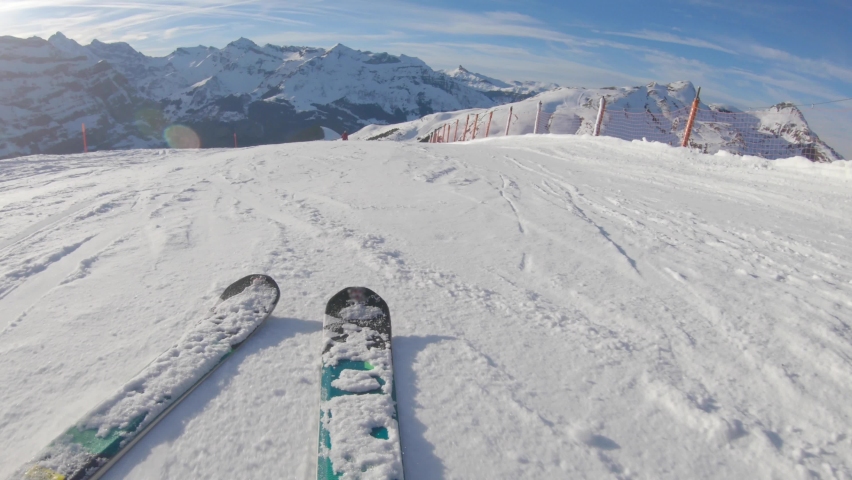 Skiing on snow slopes in the mountains, first person view - Man going downhill with ski and having fun on the slopes in the Alps, Switzerland on a sunny day - Winter sport and activities | Shutterstock HD Video #1061266717