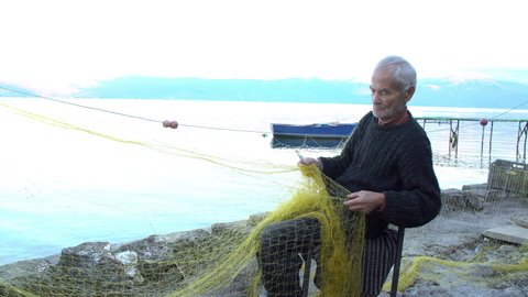 Senior fisherman holding fishing net near the beach. Fisherman hands close up. A fishermen preparing the fishing net