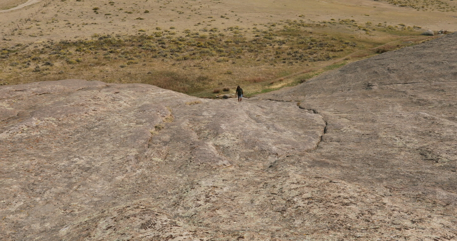 Woman climbing Independence Rock pioneer historic site Wyoming 4K. Pioneer names carved in rock. Near Martins Cove that is maintained by the Church of Jesus Christ of Latter-day Saints.