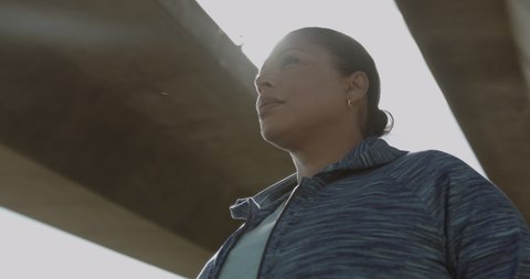 Portrait of Body positive Mature black female under bridge in city, Plus size obese overweight Latin American woman looking at camera