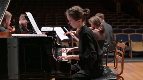 young woman playing piano with string quartet, close up