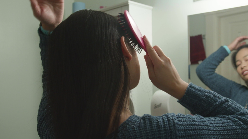 Close up young Asian woman brushing her hair in bathroom, slow motion