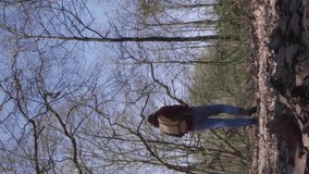 Vertical view of young female hiker walking in a bare forest landscape