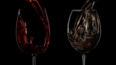 Slow motion red and white wine pouring into wine glass. Black isolated background, low key