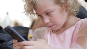 Little girl sitting and carefully studying the smartphone. Children and modern technologies