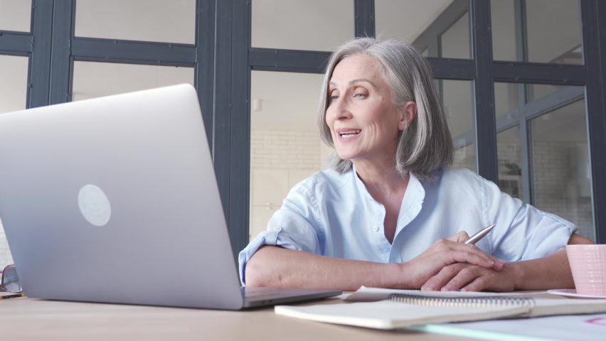 Middle aged business woman talking video conference calling on laptop. Senior old distance teacher communicating in online virtual chat remote meeting looking at computer working from home office. Royalty-Free Stock Footage #1061284720