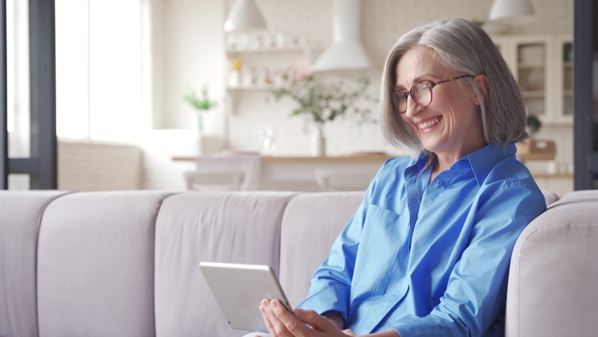 Happy old senior woman grandmother waving hand holding digital tablet video conference calling talking enjoying social distance party, virtual family online chat meeting with grandchildren at home. | Shutterstock HD Video #1061284726