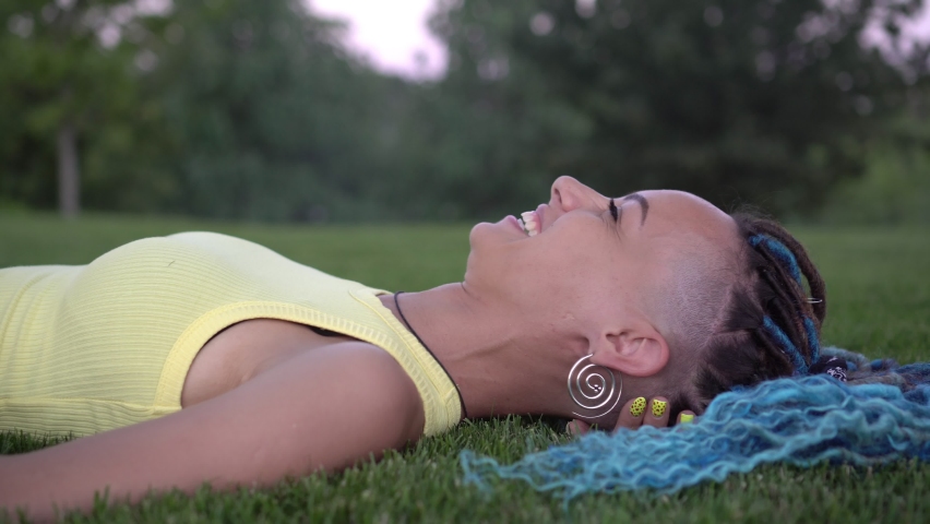 Young attractive woman lies and rests in the park on green grass