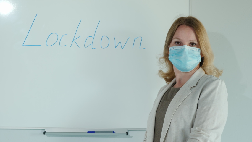 A masked teacher stands at the board with the word Lockdown written