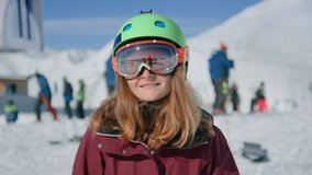 Portrait of happy young woman in green safety helmet for snowboarding and big oversize black ski goggles show peace sign, smile and laugh at camera. Happy winter holiday makes in snow mask