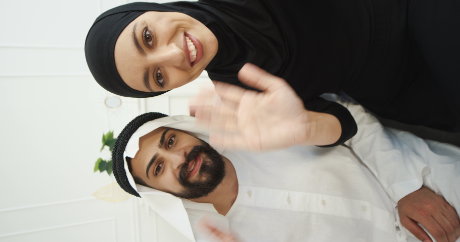 Arabs muslim married couple talking to camera when having videochat. Male and female Arabians videochatting and smiling on webcam. Middle East. Vertical orientation shot. footage for stories. Royalty-Free Stock Footage #1061290588