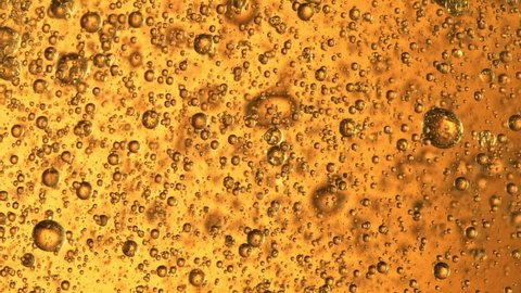 Super Slow Motion Shot of Moving Oil Bubbles in Water on Golden Background at 1000fps.