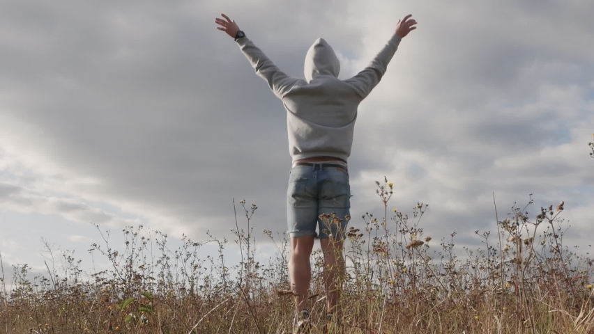 Happy guy is jumping emotionally and joyfully, a young man in nature in a hoodie jumping for joy. Happy man