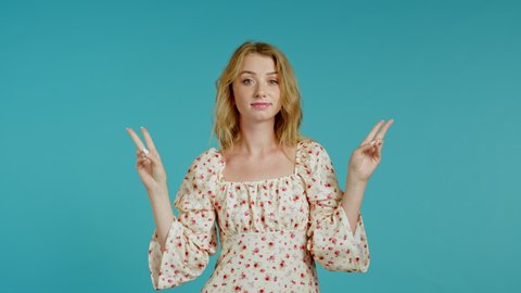 Pretty girl showing with hands and two fingers like quotes gesture, bend fingers isolated over blue background. Very funny, irony and sarcasm concept.