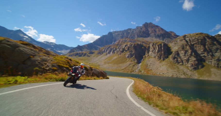 Extreme vacation concept, moto biker on a motorcycle rides a mountain road, tourist on the lake and hills in italy, freedom and enjoyment of life | Shutterstock HD Video #1061294005