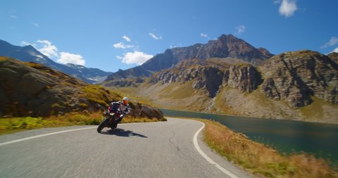 Extreme vacation concept, moto biker on a motorcycle rides a mountain road, tourist on the lake and hills in italy, freedom and enjoyment of life