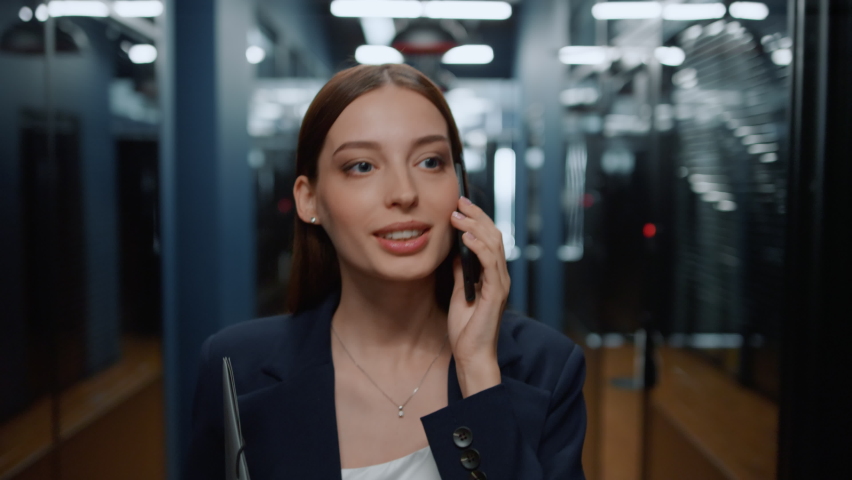 Closeup positive business woman talking smartphone in office interior. Smiling businesswoman calling mobile phone in corridor. Portrait of friendly lady walking in business center hallway. Royalty-Free Stock Footage #1061295211