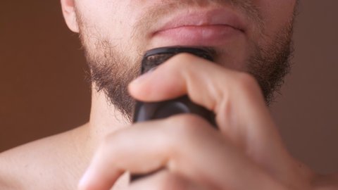 man shaves his beard with a trimmer. Electric razor for beard cutting. Close up