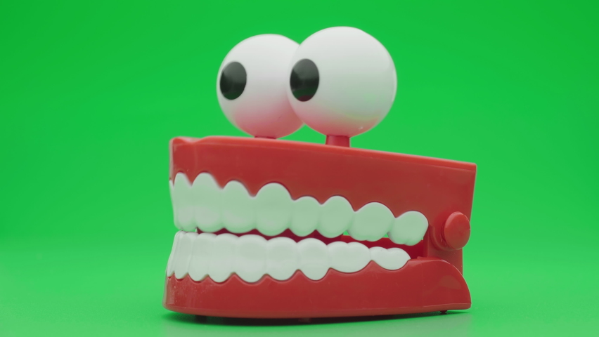 Toy teeth. Moving funny tooth model toy. Сhattering teeth toy moving on green background. | Shutterstock HD Video #1061301076