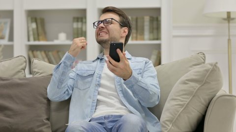 Upset Casual Young Man with Loss on Smartphone at Home