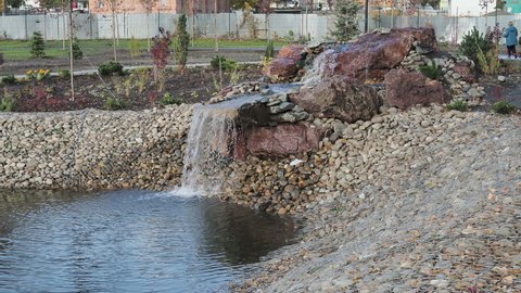 Natural stone landscaping in city park. Beautiful landscaped garden with rocks and waterfall. Nice landscape design in autumn.
