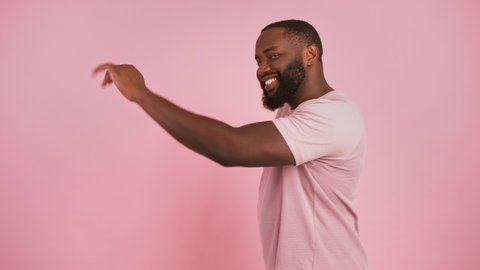 Happy african american man dancing Moon lane move, coming to shot, winking and keep dancing, pink studio background, slow motion : vidéo de stock