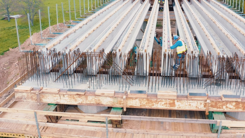 Working man on the road bridge construction. Beams with steel reinforcement from above. Royalty-Free Stock Footage #1061310589