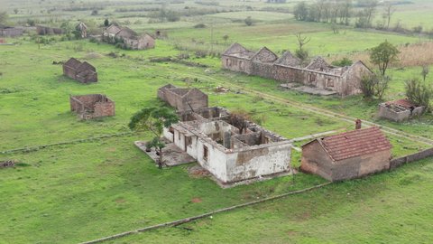Roofless derelict buildings in an abandoned farm - only walls are left of stone houses in a village deserted due to rural flight - migration to cities. Aerial view.