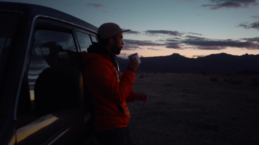 Man in puffy jacket stand outside van, sip coffee or tea, watch sunset, contemplate thoughts and find calm peace. Thoughtful camping trip in great outdoors. Camping van lifestyle Royalty-Free Stock Footage #1061318362
