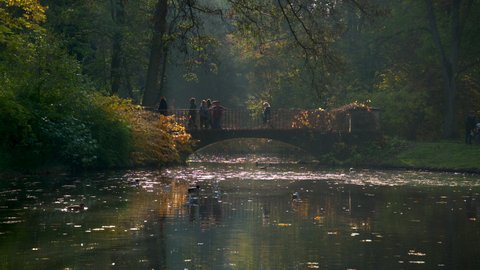 WARSAW, POLAND - OCTOBER 25, 2020: Undefined tourists walking on the small bridge in Lazienki Park. Lazienki is the largest park in Warsaw.