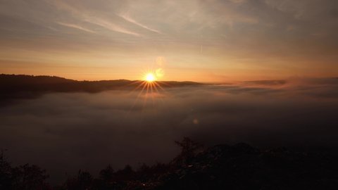 Time lapse of a sunrise with a beautiful sky above a valley with waving fog near the city Blaubeuren in the Swabian alb.