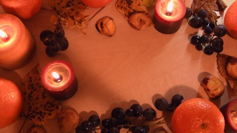 Top view of an autumnal background with leaves, mandarin, chestnuts, candels and grapes