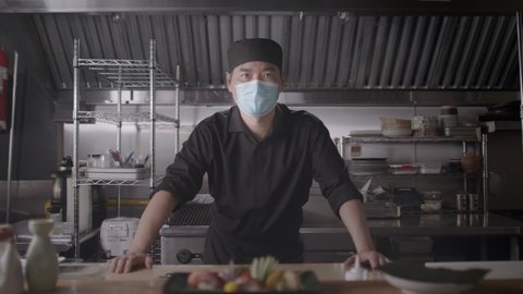Japanese Chef and small business owner wearing a mask. Professional sushi chef portrait. Shot in 4k. 
