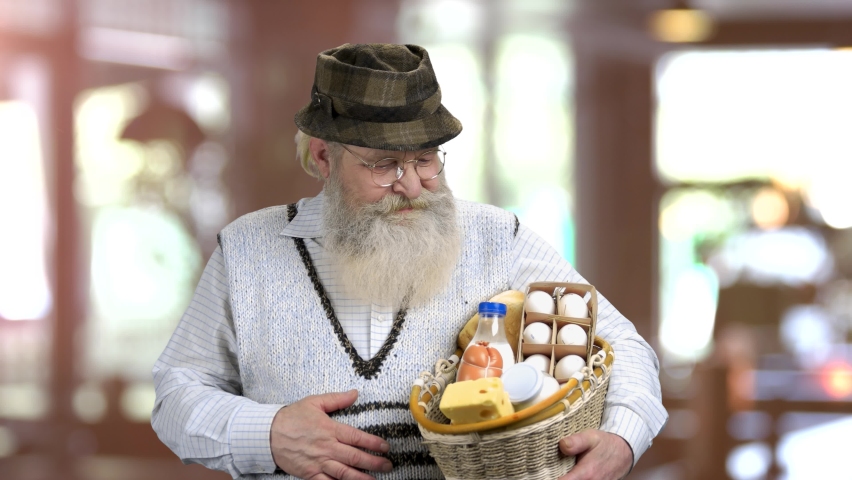 Happy bearded man holding basket of dairy products. Abstract blurred background. Natural healthy food concept.