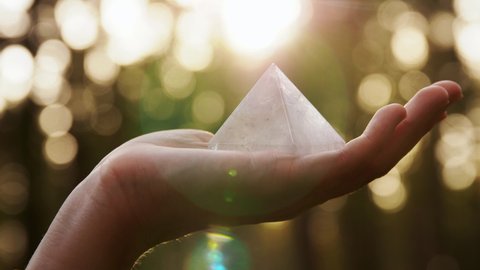 occult science and supernatural concept - hand with pyramid performing magic ritual in forest