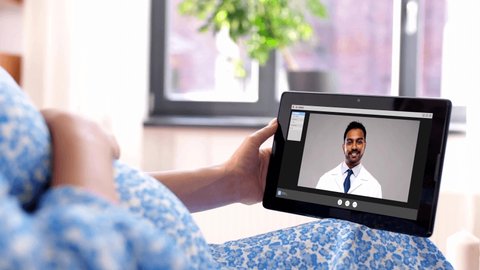 pregnancy, technology and medicine concept - happy pregnant woman with tablet pc computer having video call with indian doctor at home