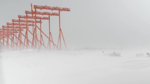 Low angle shot of Airport lights being punished by heavy blizzard and strong winds, in the midst of a white snowy vastness, in Sweden